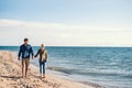 Young couple walking outdoors on beach, holding hands. Copy space. Royalty Free Stock Photo