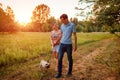 Young couple walking pug dog in autumn forest. Happy puppy running along and having fun playing with master. Royalty Free Stock Photo