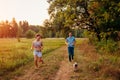 Young couple walking pug dog in autumn forest. Happy puppy running along and having fun playing with master. Royalty Free Stock Photo