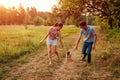 Young couple walking pug dog in autumn forest. Happy puppy running along and having fun playing with masters. Royalty Free Stock Photo