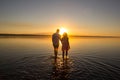 Young couple is walking in the water on summer beach. Sunset over the sea.Two silhouettes against the sun. Just married couple Royalty Free Stock Photo