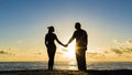 Young couple is walking in the water on summer beach. Sunset over the sea.Two silhouettes against the sun. Just married Royalty Free Stock Photo