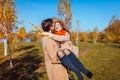 Young couple walks in autumn forest. Man carrying his girlfriend in hands and laughing Royalty Free Stock Photo