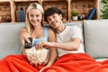 Young couple watching film and eating popcorn sitting on the sofa at home Royalty Free Stock Photo