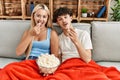 Young couple watching film and eating popcorn sitting on the sofa at home Royalty Free Stock Photo