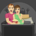 Young couple watching horror movie at home sitting with popcorn on sofa Royalty Free Stock Photo