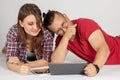 Young couple watching media content online in a tablet lying down and laughing. Wearing casual, stylish and funny.