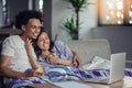 Young couple watching a movie on their laptop in bed