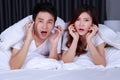 Couple watching scared movie on bed in the bedroom