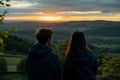 young couple watching sunrise from an undiscovered hilltop