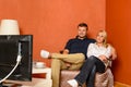 Young couple watching tv cuddling sitting armchair