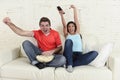 Young couple watching tv sport football game excited celebrating