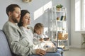 Young couple watching video on laptop while their little child is using modern mobile phone Royalty Free Stock Photo