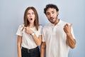 Young couple wearing casual clothes standing together surprised pointing with finger to the side, open mouth amazed expression Royalty Free Stock Photo