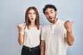 Young couple wearing casual clothes standing together surprised pointing with hand finger to the side, open mouth amazed Royalty Free Stock Photo