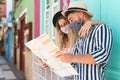 Young couple wearing face mask and holding travel map - Travelers people enjoying first trip after corona virus outbreak Royalty Free Stock Photo