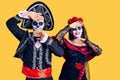 Young couple wearing mexican day of the dead costume over background smiling cheerful playing peek a boo with hands showing face