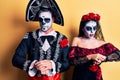 Young couple wearing mexican day of the dead costume over yellow checking the time on wrist watch, relaxed and confident Royalty Free Stock Photo