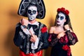 Young couple wearing mexican day of the dead costume over yellow in hurry pointing to watch time, impatience, looking at the Royalty Free Stock Photo