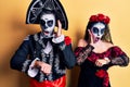 Young couple wearing mexican day of the dead costume over yellow looking at the watch time worried, afraid of getting late Royalty Free Stock Photo