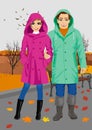 Young couple wearing raincoats standing in park in autumn