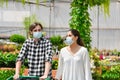 A young couple wearing surgical masks pushing a shopping cart at a garden center. Safety and shopping concept Royalty Free Stock Photo