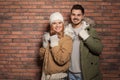 Young couple wearing warm clothes against wall, space for text. Ready for winter vacation