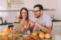 Couple websurfing with tablet in home kitchen Royalty Free Stock Photo