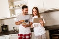 Couple websurfing with tablet in home kitchen Royalty Free Stock Photo