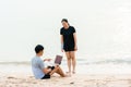 The young couple were chatting to their colleagues via video, on their laptop computers, on the sandy beach where the slow waves Royalty Free Stock Photo