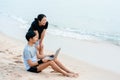 The young couple were chatting to their colleagues via video, on their laptop computers, on the sandy beach where the slow waves Royalty Free Stock Photo