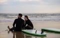 Young Couple In Wetsuits Relaxing On The Beach After Surfing Royalty Free Stock Photo