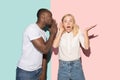 The young couple whispering a secret behind her hand over studio background Royalty Free Stock Photo