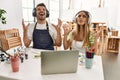 Young couple of wife and husband at art studio looking at video on laptop crazy and mad shouting and yelling with aggressive Royalty Free Stock Photo