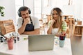 Young couple of wife and husband at art studio looking at video on laptop serious face thinking about question with hand on chin, Royalty Free Stock Photo