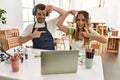 Young couple of wife and husband at art studio looking at video on laptop smiling making frame with hands and fingers with happy Royalty Free Stock Photo