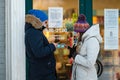 A young couple in winter clothes stands at the entrance of the store and looks at a smartphone