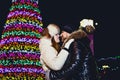 Young couple in winter fur clothes hugging under chimes on Christmas night Royalty Free Stock Photo