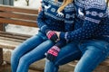 Young couple winter warm sweaters and jeans hugging in the Park in winter sitting on a wooden bench Beautiful young couple in love Royalty Free Stock Photo