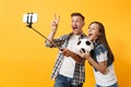 Young couple, woman man, football fans doing selfie on mobile phone with monopod selfish stick, cheer up support team Royalty Free Stock Photo