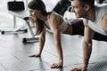 Young couple is working out at gym. Attractive woman and handsome muscular man are training in light modern gym. Doing plank.Push- Royalty Free Stock Photo