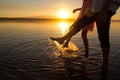 Young couples is walking in the water on summer beach. Sunset over the sea.Two silhouettes against the sun. Feet doing splashes of Royalty Free Stock Photo