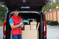 Young courier checking amount of parcels in delivery van