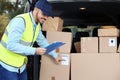 Young courier checking amount of parcels in delivery van