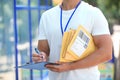 Young courier with padded envelopes and clipboard, closeup. Delivery service