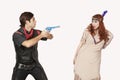 Young cowboy aiming gun at woman in old-fashioned costume against gray background Royalty Free Stock Photo