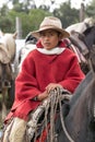 Young cowboy on horse back wearing red poncho