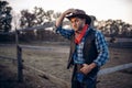 Young cowboy poses against horse corral