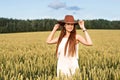 Young cowboy woman in summer on a yellow wheat field