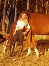 Young cowgirl with her red horse at sunset. Royalty Free Stock Photo